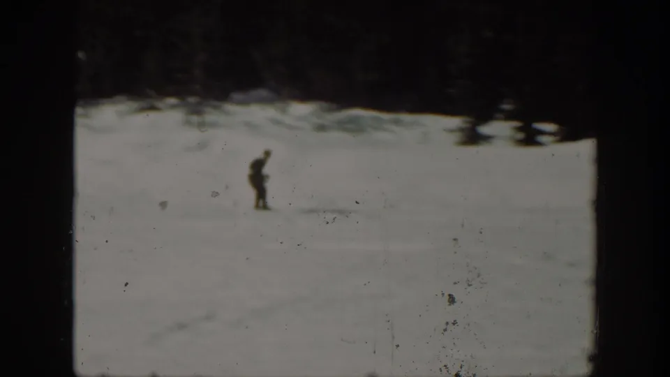 Distant skier in dark clothing on a bright 1940 Washington snow slope, with trees and film wear visible around the frame.