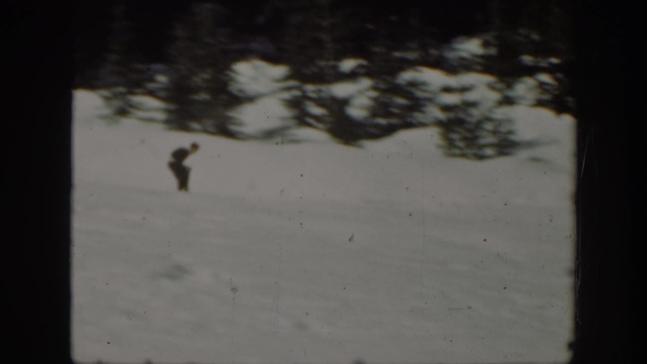 A distant skier in dark clothing stands or moves on a snow-covered Washington hillside in 1940s 8mm home-movie footage.