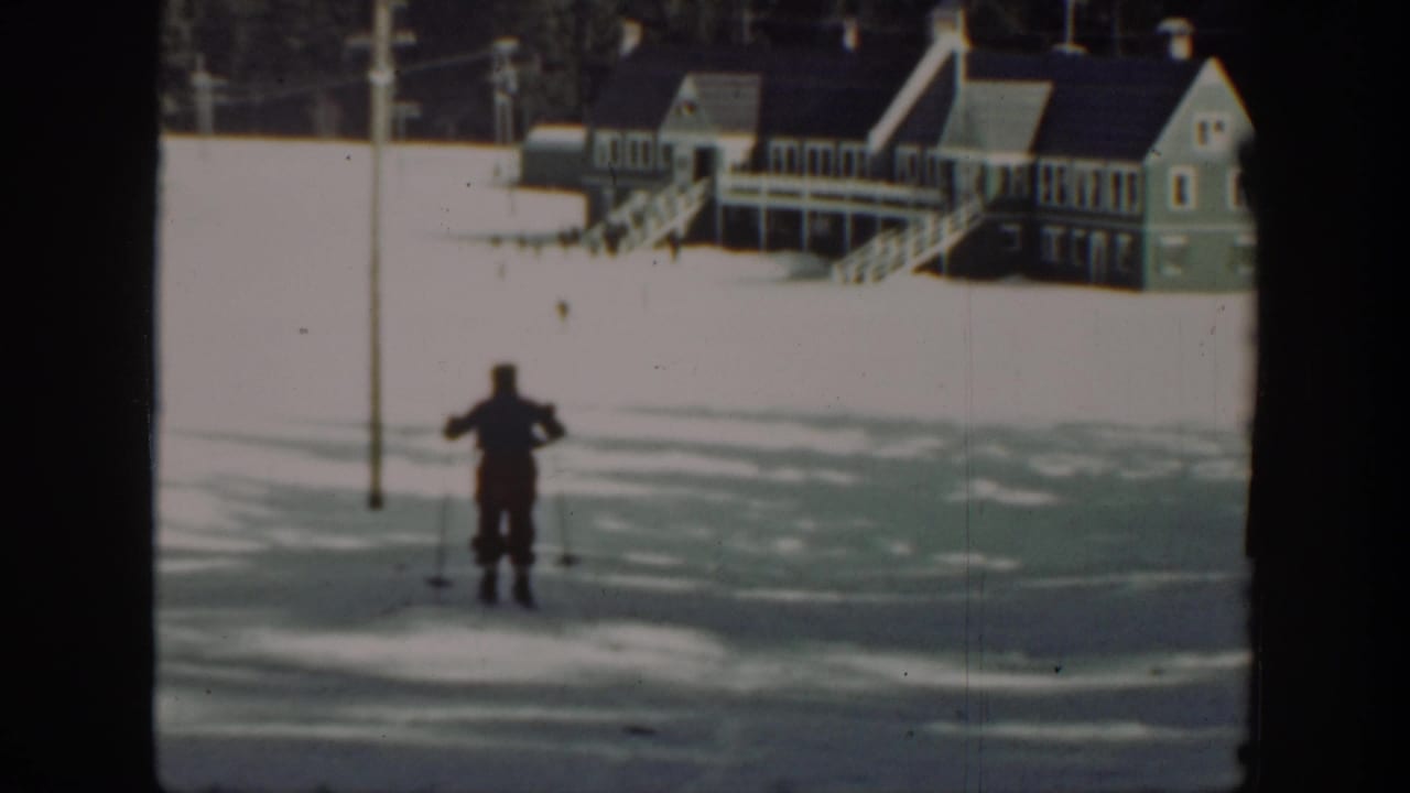 In 1940s Washington home-movie footage, a lone skier moves across snow below wooden buildings and utility poles.