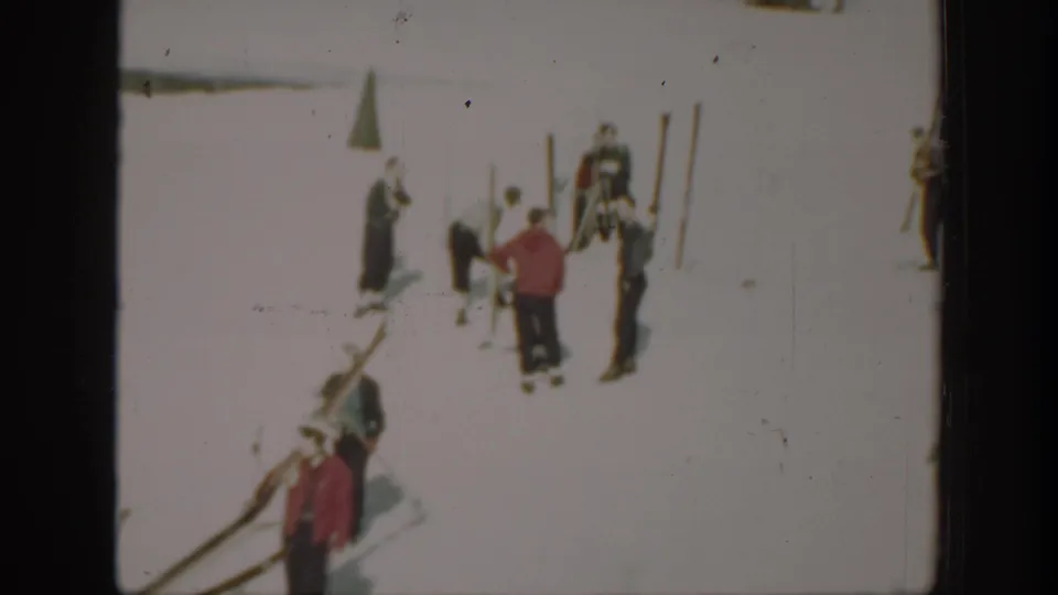 Several skiers in winter clothing gather on a snowy Washington resort area, with long skis and upright poles visible around them.