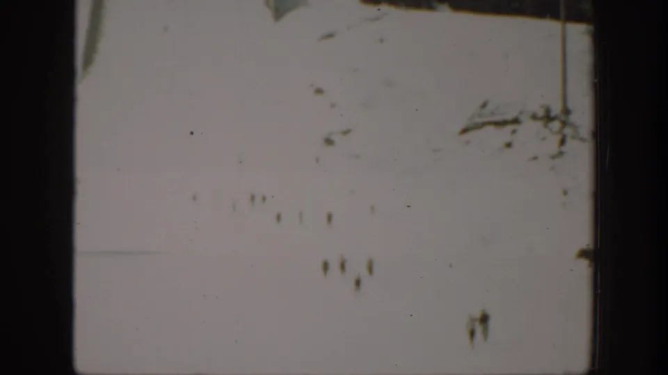 Soft 8mm frame from Washington footage showing a bright snowfield with indistinct distant marks or possible figures.