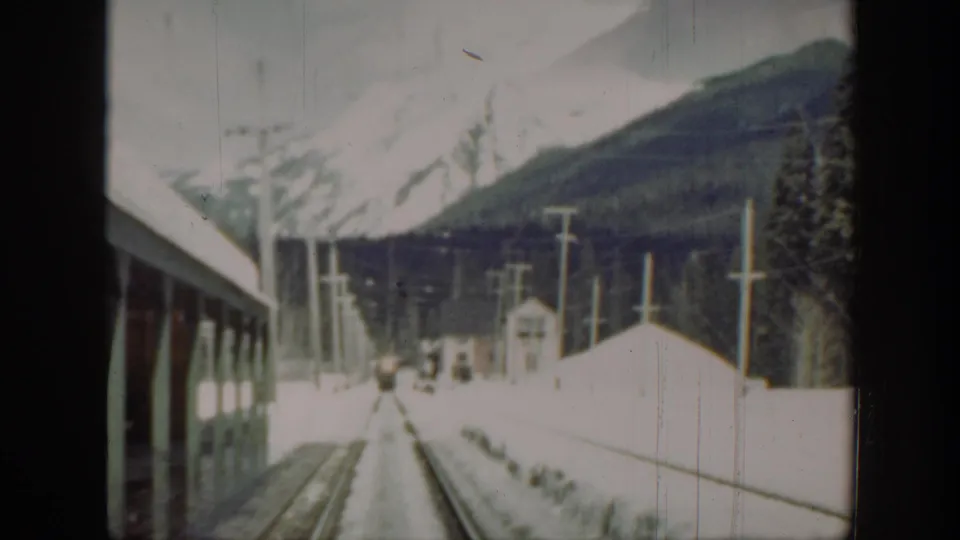 Snowy Washington mountain railway view with tracks leading ahead, utility poles lining the route, and a small rail-side structure near the center.