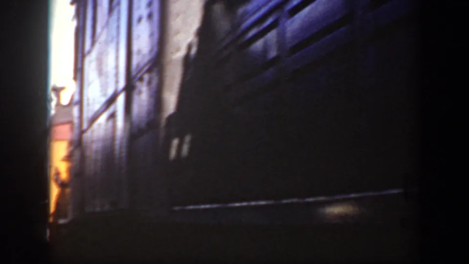 The side of the passing train dominates the final frame, with dark metal panels and a sliver of snowy outdoor light at the edge.