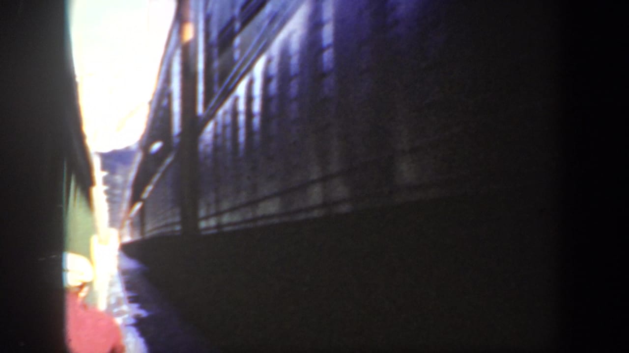 Washington 1940 home-movie frame showing shadowed train-car sides and a bright opening beyond the narrow passage.