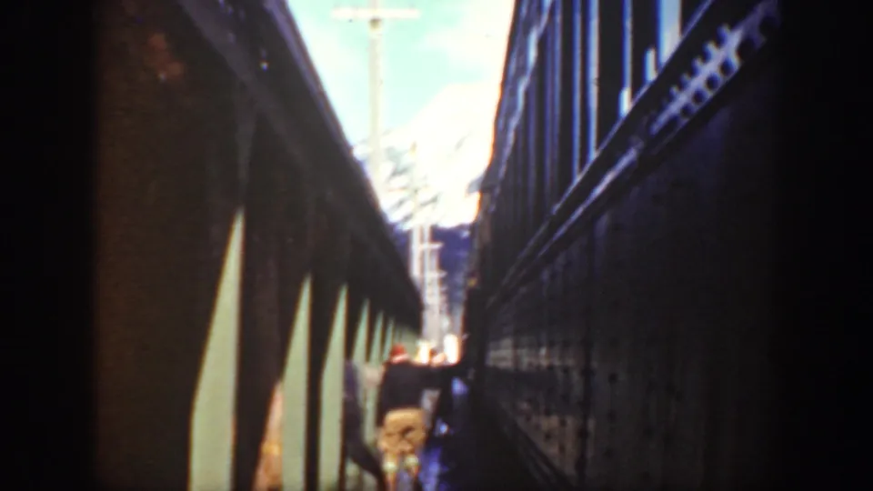 Washington 1940 frame showing passengers beside shadowed train cars, including a partly visible face and red cap near the lower center.
