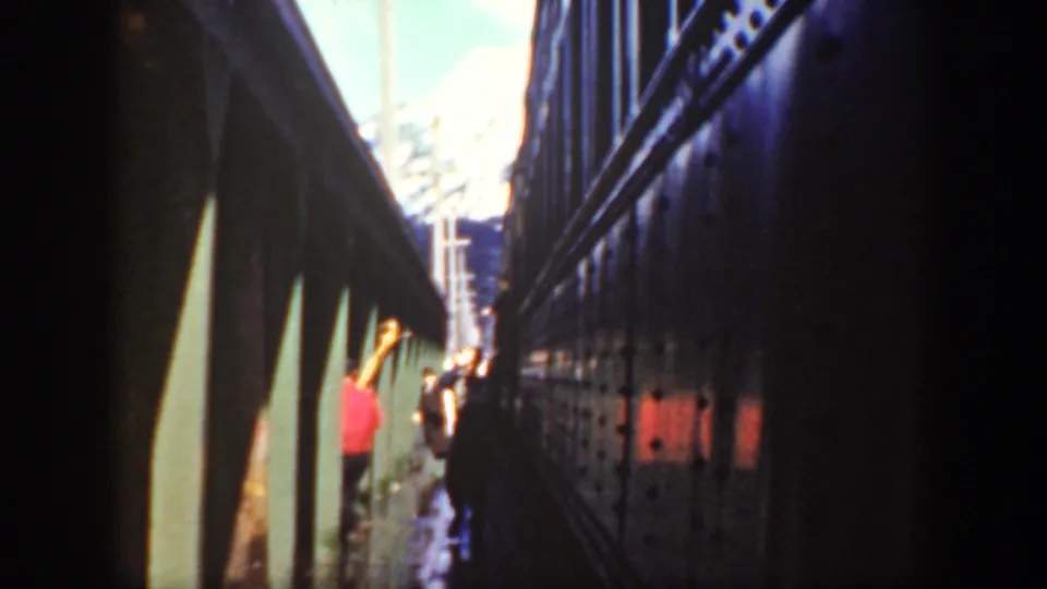 People walk through a narrow Washington passage beside a dark train or rail car, filmed handheld on 8mm in 1940.