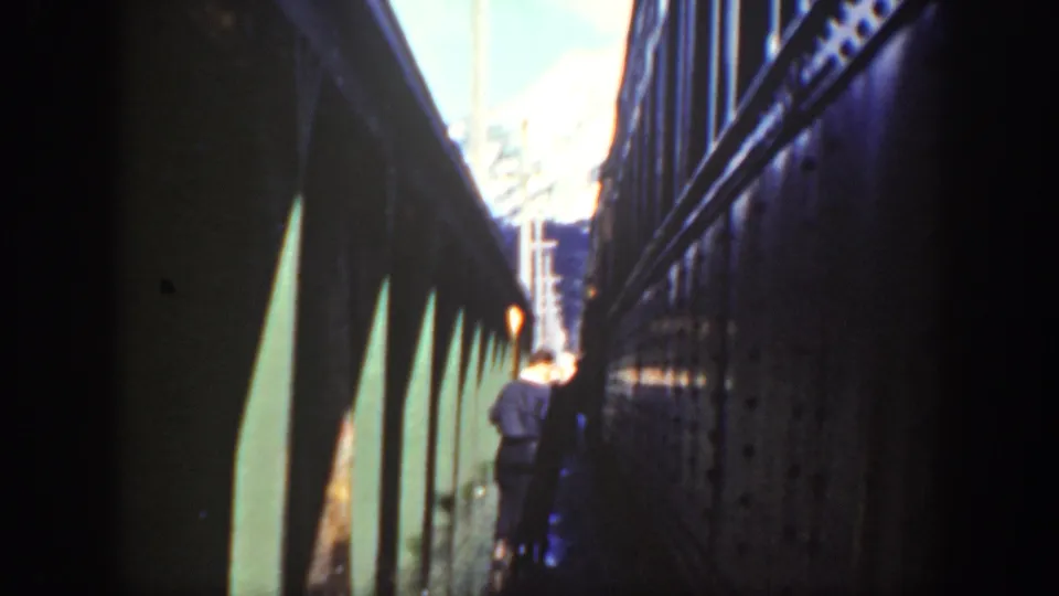 Washington 1940 home-movie frame showing a tight walkway between train cars and a distant person moving away from the camera.