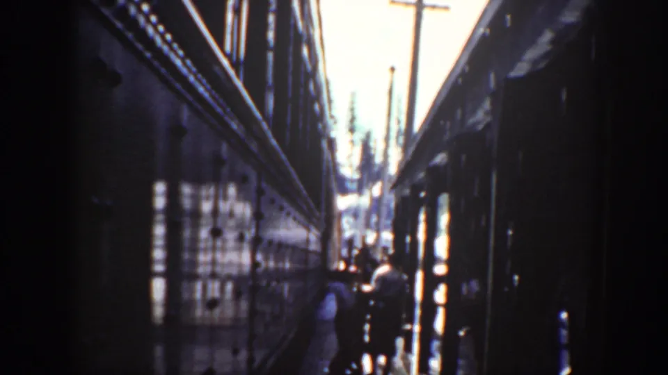 A 1940 Washington home-movie view down the space between train cars, with people visible near the brighter end of the passage.