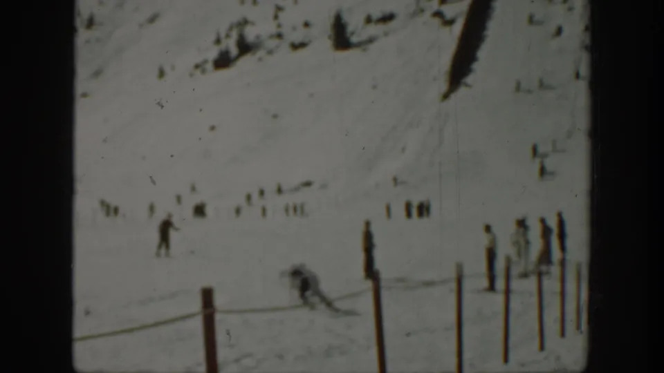 1940 Washington 8mm frame with distant skiers and spectators spread across a snow-covered mountain slope behind a rope line.