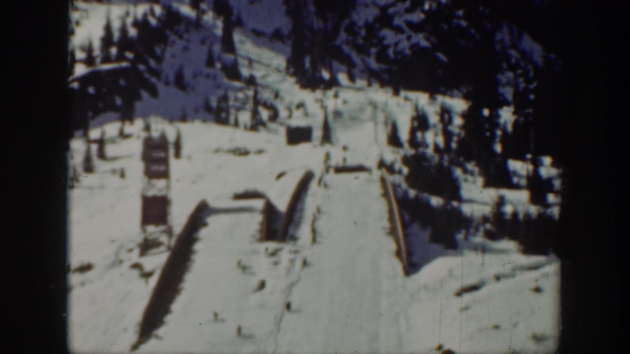1940 Washington home-movie frame showing a snow-covered ski slope, wooden structures, and evergreen trees in the background.