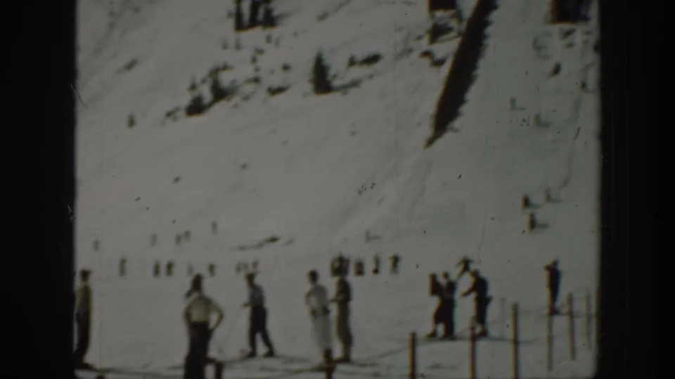 Washington 1940 ski-area view with onlookers near a fence and small figures across the snowy slope.