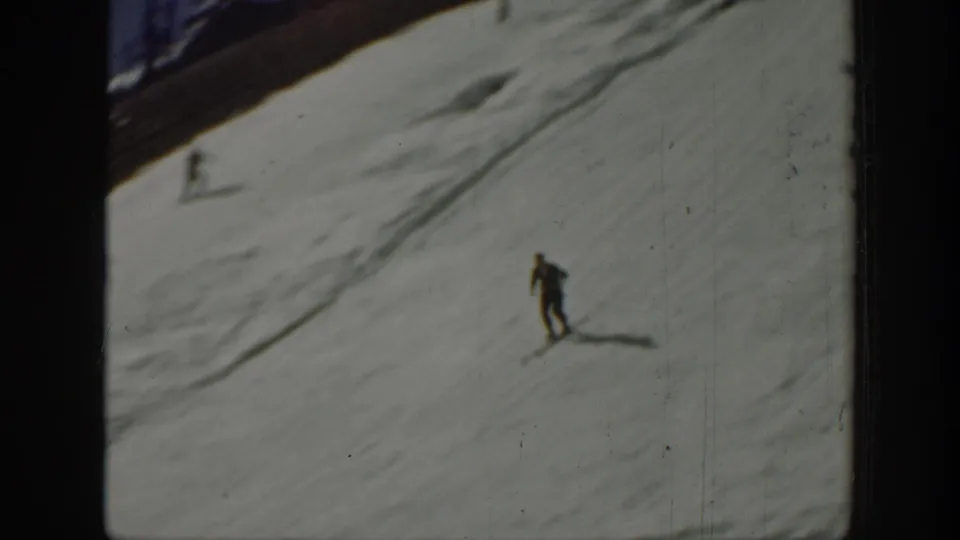 Distant skier in dark clothing crossing a bright snowfield in the 1940 Washington ski-jump home-movie scene.