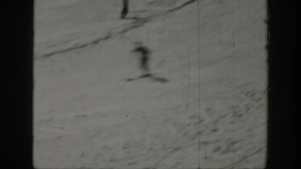 A skier appears blurred in motion while descending a snow-covered slope in the 1940 Washington ski footage.