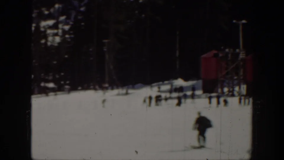 1940 Washington ski-area view with a skier in the foreground, scattered people, trees, and a small red structure in the background.