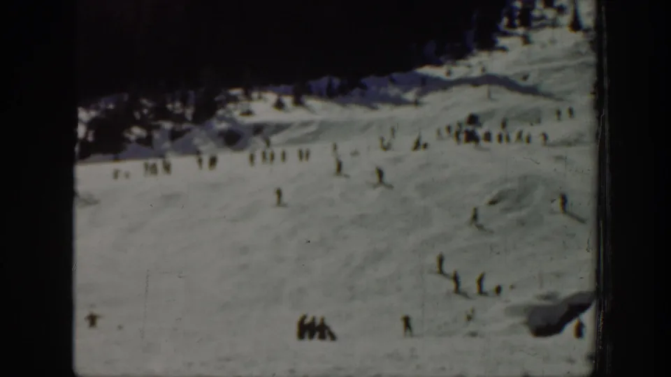 Washington 1940 8mm frame showing a broad snow-covered ski area with tiny skiers and groups near the lower slope.