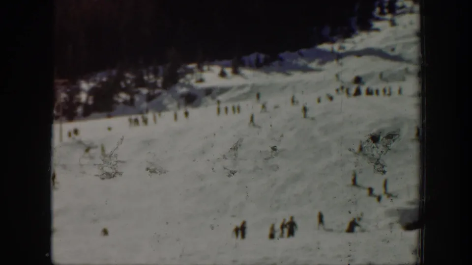 Wide 1940 Washington ski scene with distant skiers gathered and moving across a snow-covered mountain slope.