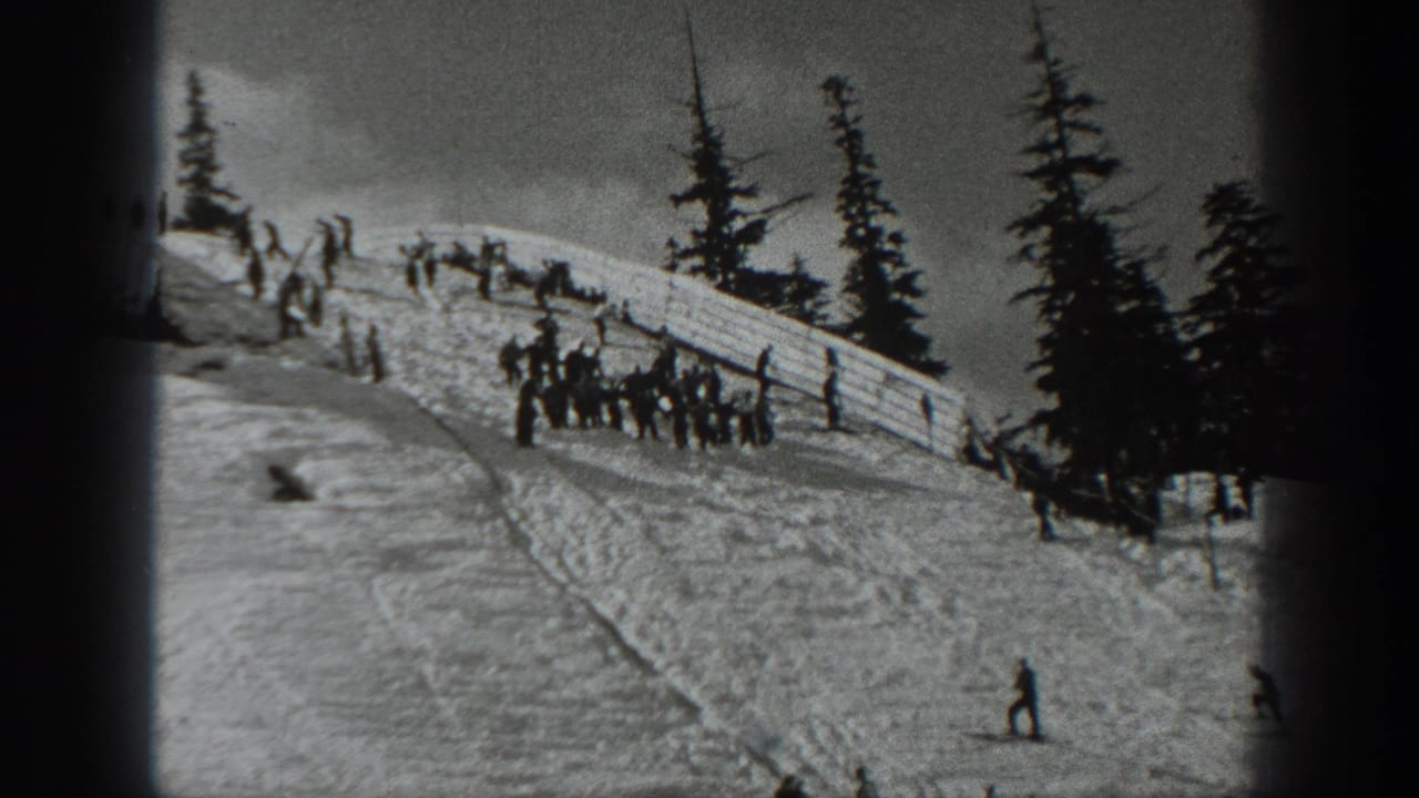 Black-and-white 1940 Washington frame with skiers and spectators gathered near a wooden fence on a snowy hill.