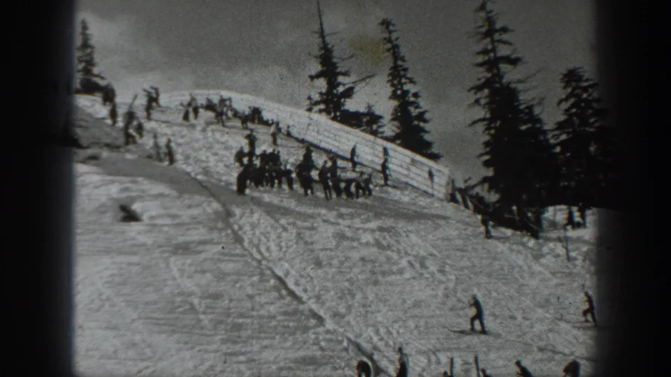 Black-and-white 1940 Washington home-movie frame showing a crowded upper slope and skiers below on packed snow.