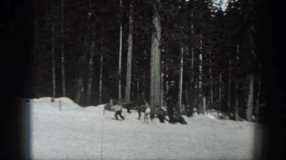 Black-and-white 1940 Washington home-movie frame with several distant people near the edge of a snowy evergreen forest.