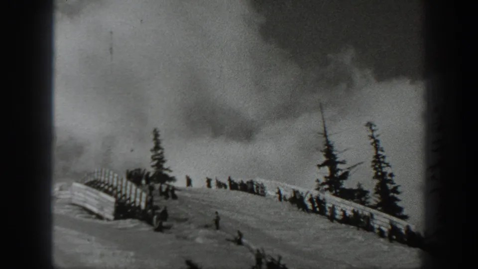 1940 Washington 8mm frame showing lingering smoke over a snow-covered slope with distant people and evergreen trees.