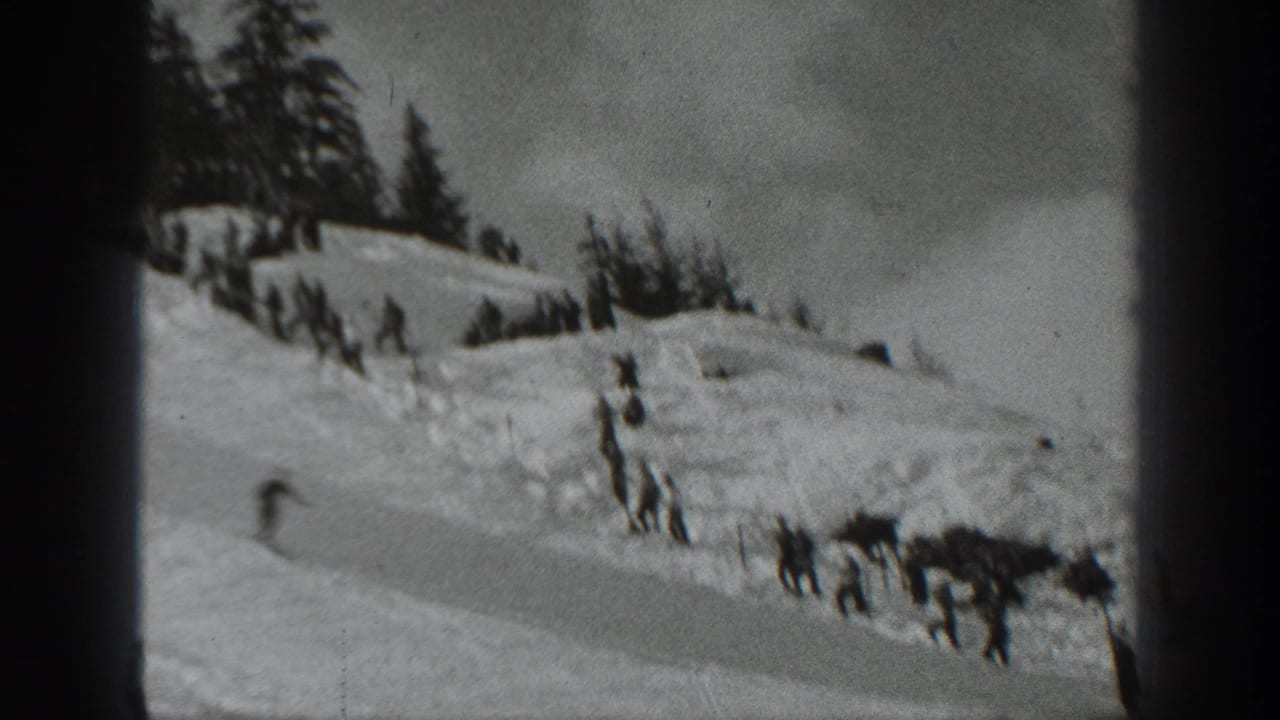 A lone skier descends a snowy slope with evergreens above and film borders at the sides.