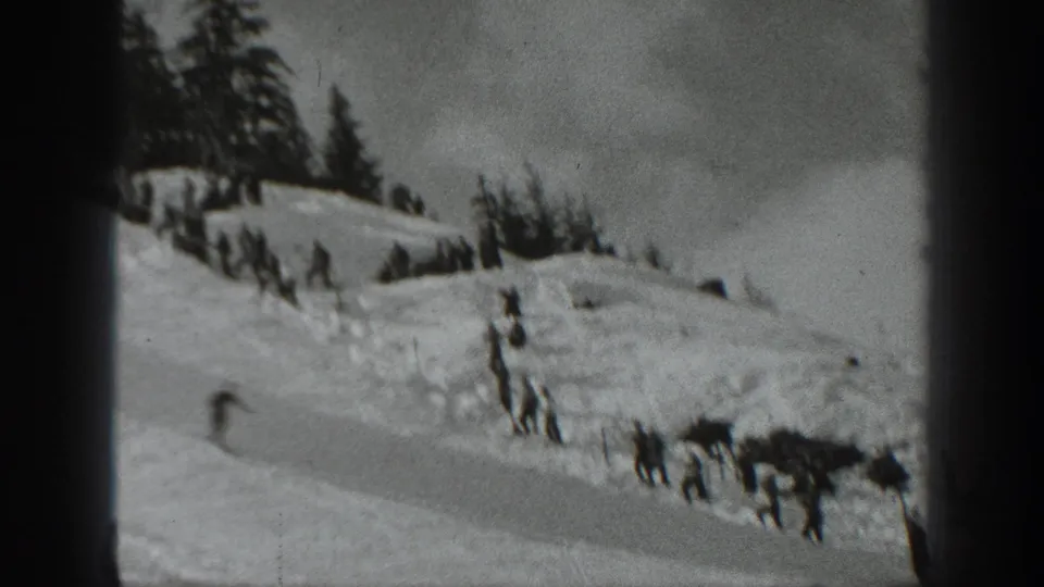 Black-and-white 1940 Washington home-movie frame showing a skier on a snowy mountain slope beneath evergreen trees.
