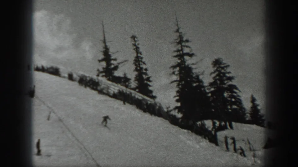 1940 Washington frame with a lone skier moving down a snowy hillside below silhouetted evergreens and a ridge fence.