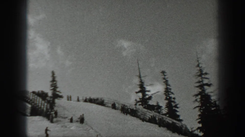 1940 Washington home-movie view of a snowy ridge where small groups gather near fencing among evergreen trees.