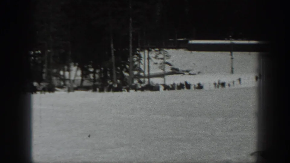 Wide 1940 Washington ski-area view showing people gathered near a tree line at the base of a snow-covered slope.