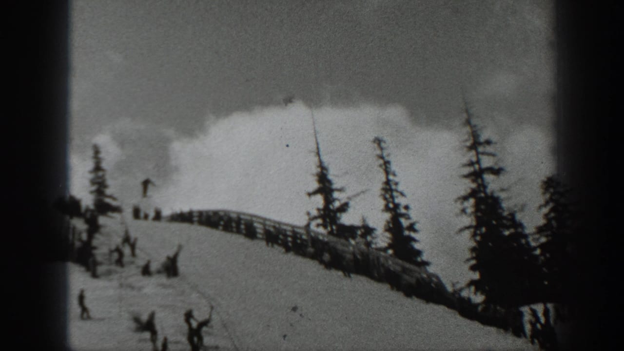 1940 Washington 8mm frame showing a snowy ski slope with evergreen trees, a fence line, and skiers or spectators gathered near the hill.