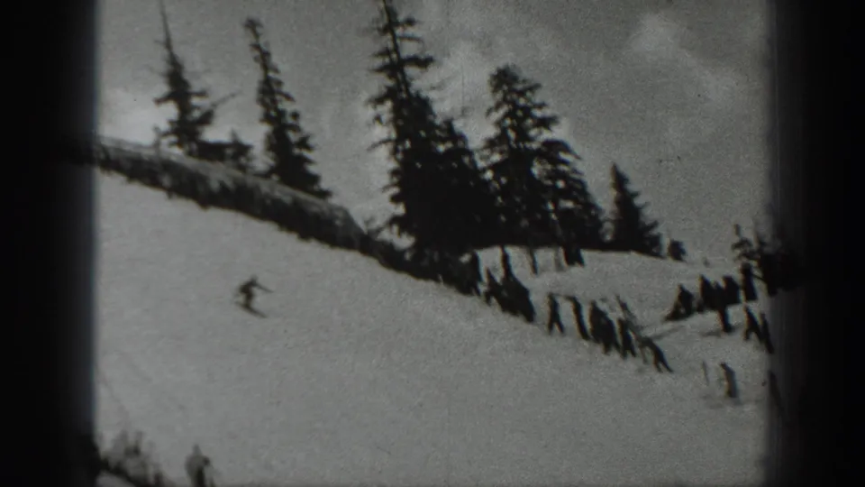 Black-and-white 8mm frame from Washington in 1940 with a skier on an open snowy slope and trees along the ridge.
