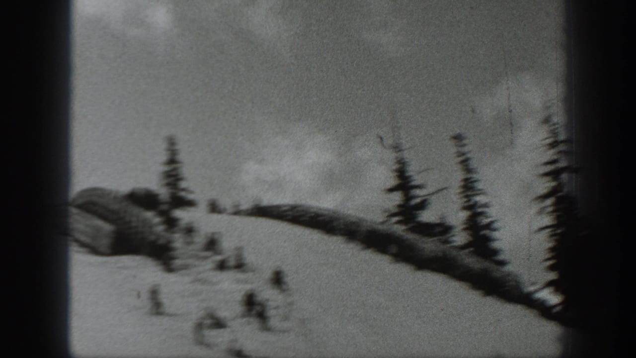 1940 Washington 8mm frame showing distant skiers on a snowy slope with pine trees and heavy gate shadows.