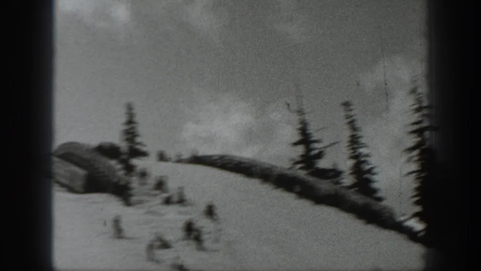 1940 Washington 8mm frame showing distant skiers on a snowy slope with pine trees and heavy gate shadows.