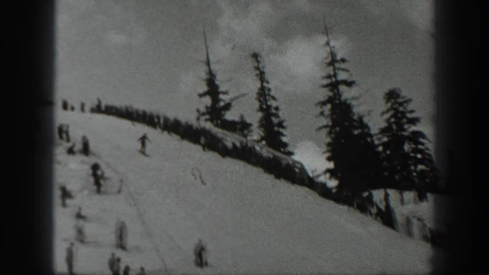 1940 Washington home-movie frame showing skiers below a spectator ridge in a snowy evergreen landscape.