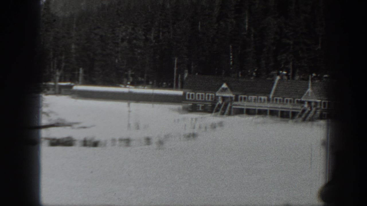 Black-and-white 1940 Washington home-movie frame showing a snow-covered resort building beside evergreen forest.