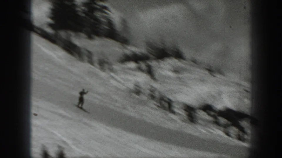 A distant skier moves downhill on a snowy Washington slope in a soft black-and-white 8mm frame.