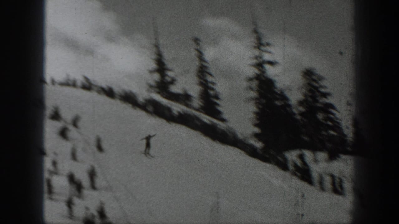 1940 Washington ski footage frame showing distant skiers on a snow-covered slope bordered by dark evergreen trees.