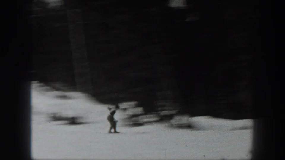 A skier appears low in frame against bright snow while motion blur and heavy shadow obscure much of the slope.