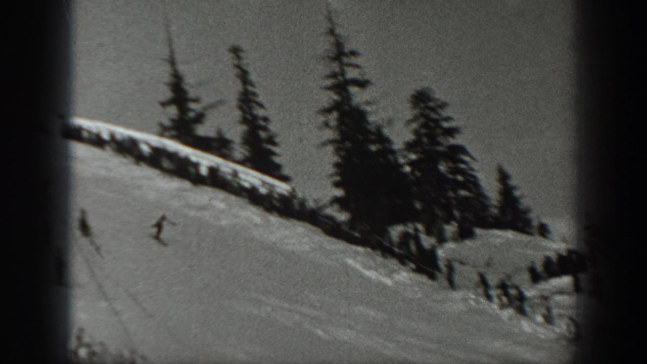 1940 Washington 8mm frame showing a distant skier on a snowy mountain slope with dark evergreens along the ridge.