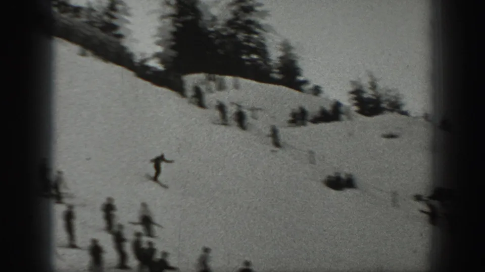 Wide 8mm view of a snowy Washington slope with one skier in motion and several people standing lower on the hill.