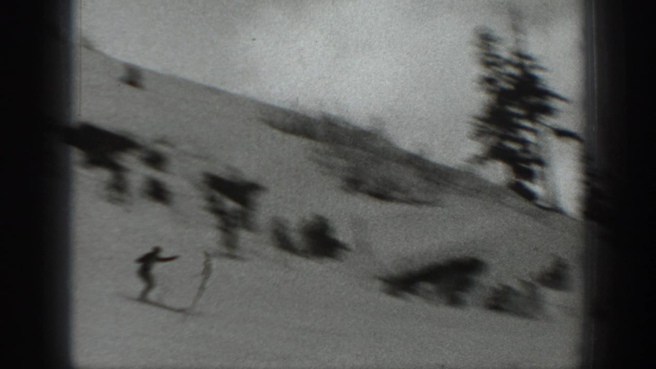 1940s Washington 8mm frame showing a skier descending a snowy slope with evergreen trees and distant skiers nearby.