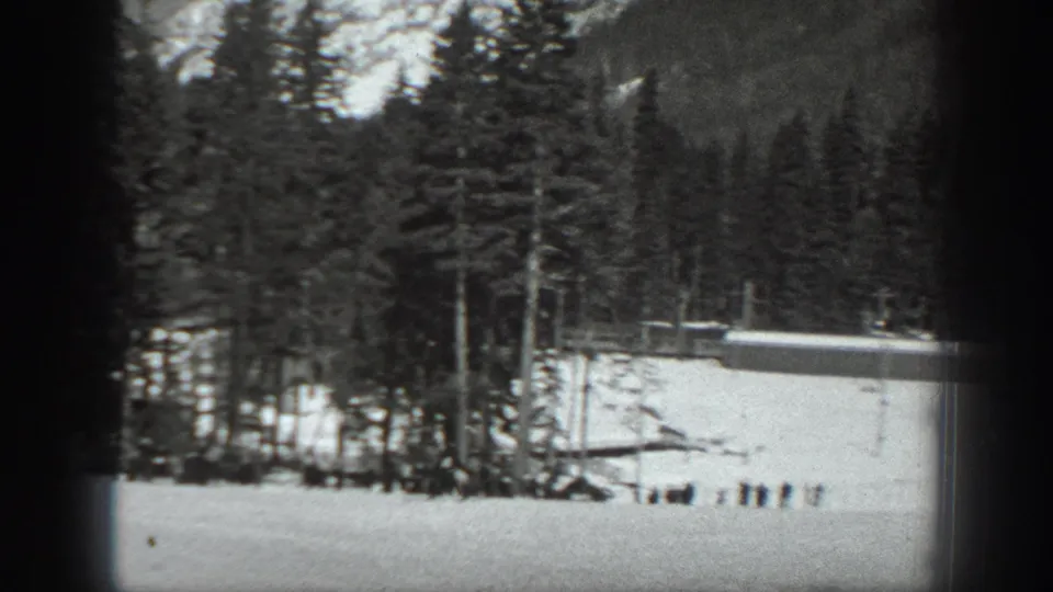 Washington winter recreation scene with snow, evergreen forest, small distant figures, and a possible ski-lift or slope structure.