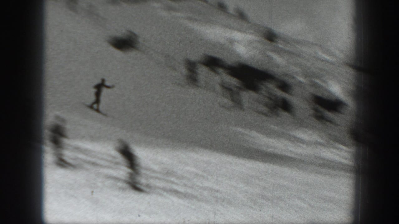A skier descends a Washington snow slope in 1940, with blurred figures and course terrain visible in the background.