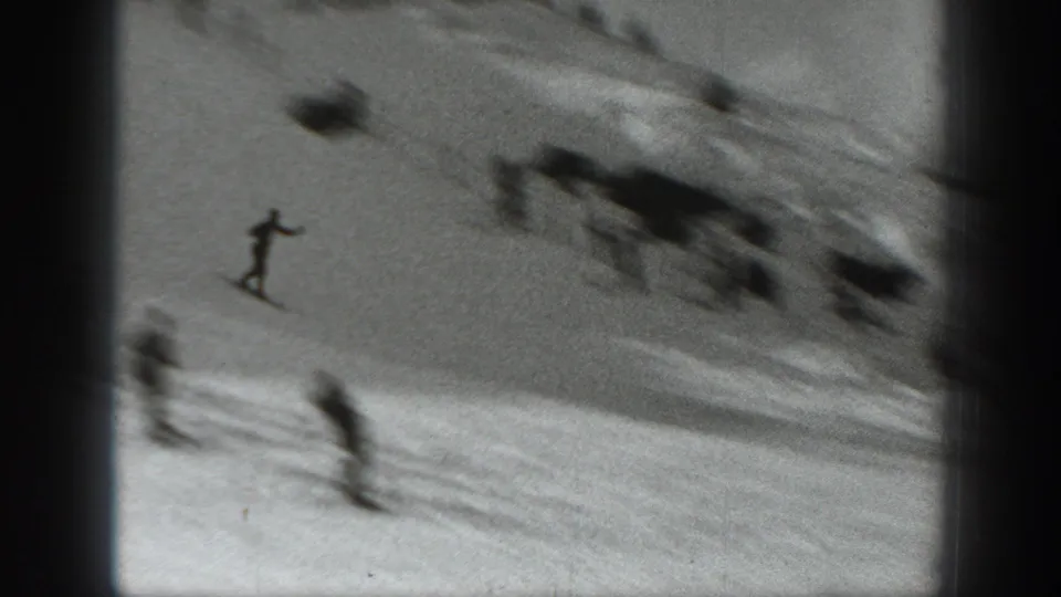 A skier descends a Washington snow slope in 1940, with blurred figures and course terrain visible in the background.