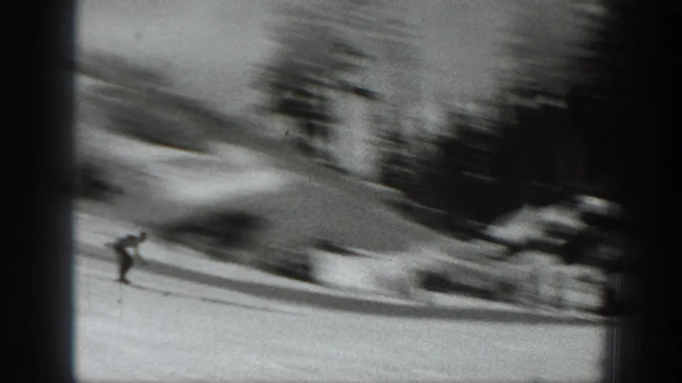 1940 Washington home-movie frame of a skier descending a snowy slope, with motion-blurred trees behind.