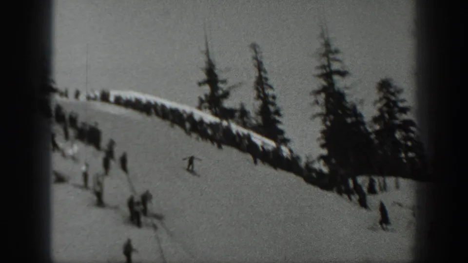1940 Washington home-movie frame showing skiers and spectators on a snowy mountain slope with dark evergreen trees.