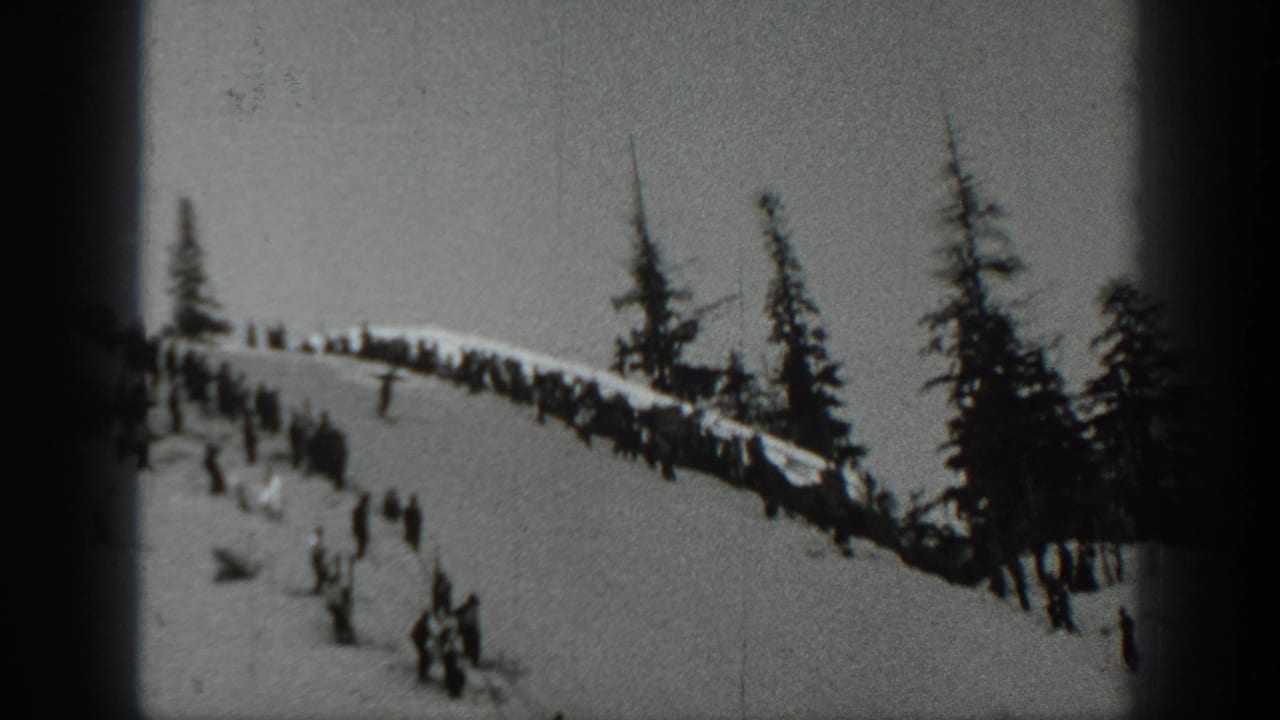 1940 Washington 8mm frame showing spectators gathered on a snowy slope near evergreens and a ski-jump area.