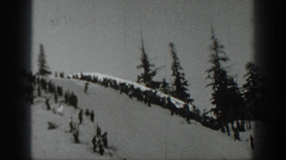 1940 Washington 8mm frame showing spectators gathered on a snowy slope near evergreens and a ski-jump area.