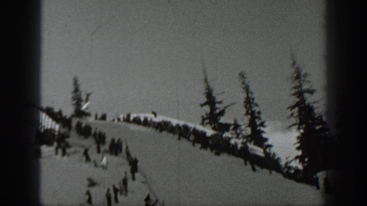 1940 Washington 8mm frame showing a snowy ski slope, scattered skiers, evergreens, and a dark film gate edge.