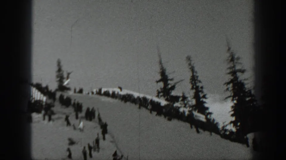 1940 Washington 8mm frame showing a snowy ski slope, scattered skiers, evergreens, and a dark film gate edge.